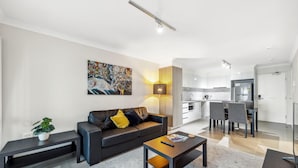 A modern living room with a sofa, coffee table, and artwork. - Rockingham Relaxed Apt | Fast Wi-fi + Free Parking - 2 Bed 2 Bath Standard (Rockingham)