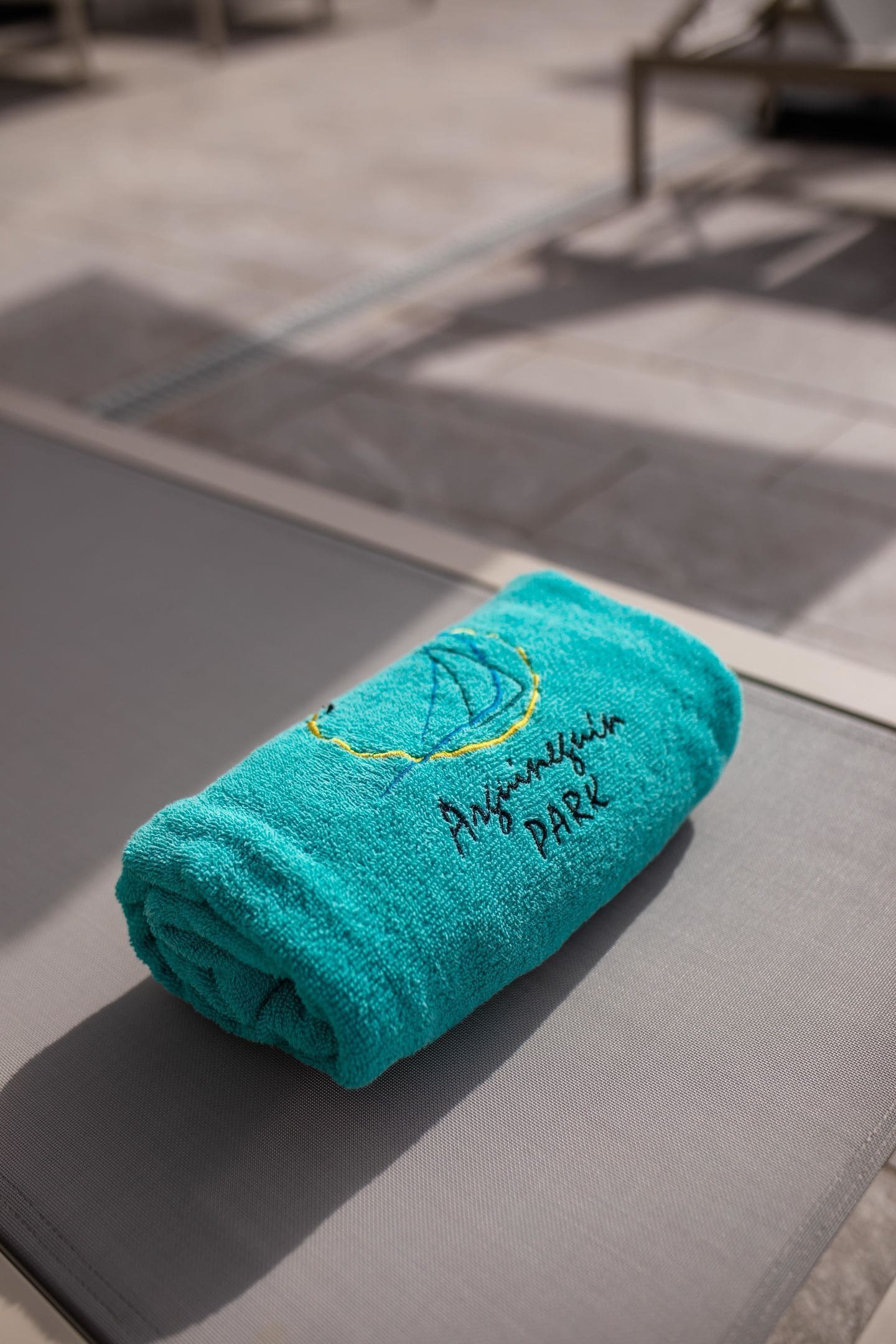 A folded teal towel with embroidered text on a textured surface.
