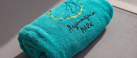 A folded teal towel with embroidered text on a textured surface.