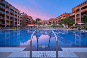 A hotel pool area with clear blue water, sun loungers, umbrellas, and a view of the surrounding buildings. - Arguineguin Park By Servatur VV (Mogan)