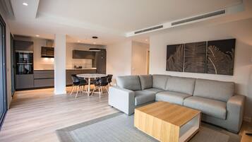 Una sala moderna con un sofá seccional gris, una mesa de centro de madera y un comedor con una mesa redonda y sillas.