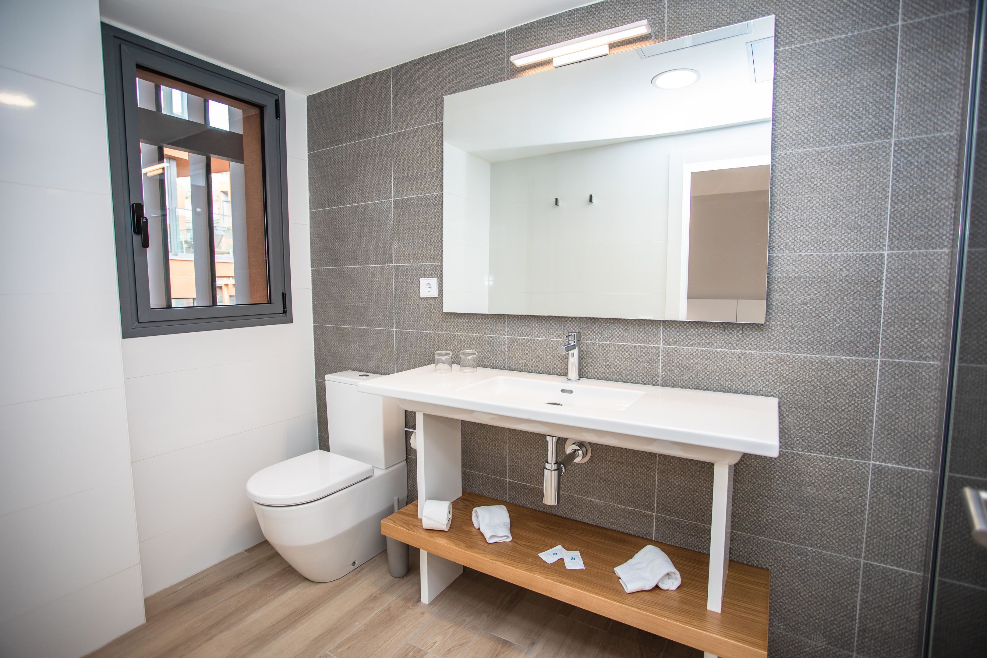 A modern bathroom with a white sink, a mirror, and a toilet.