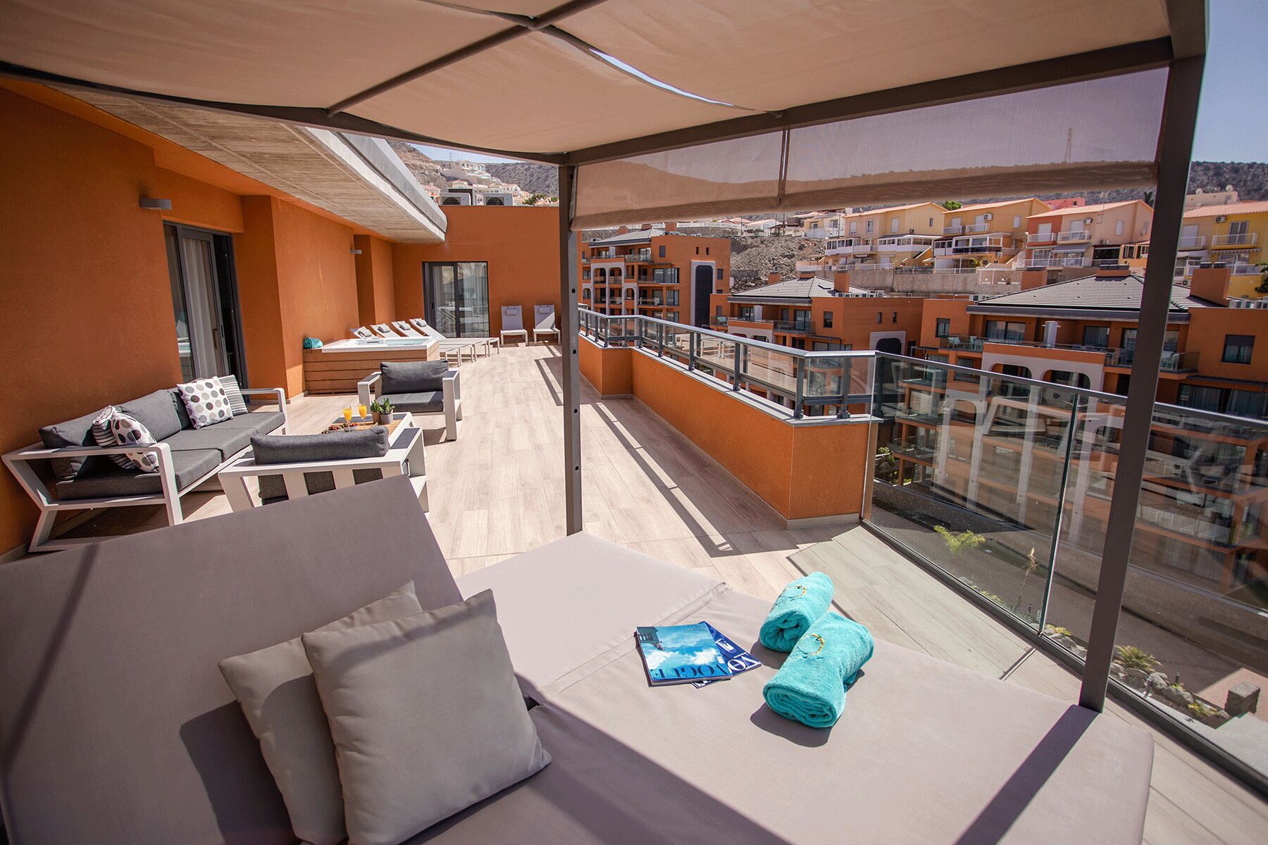 Een balkon met een bank, stoelen en een tafel, met uitzicht op een woongebied.