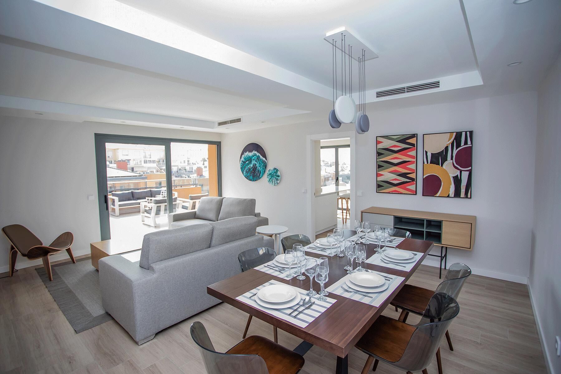 Un salon moderne comprenant un coin repas, un canapé, une table basse et une table à manger pour six personnes.