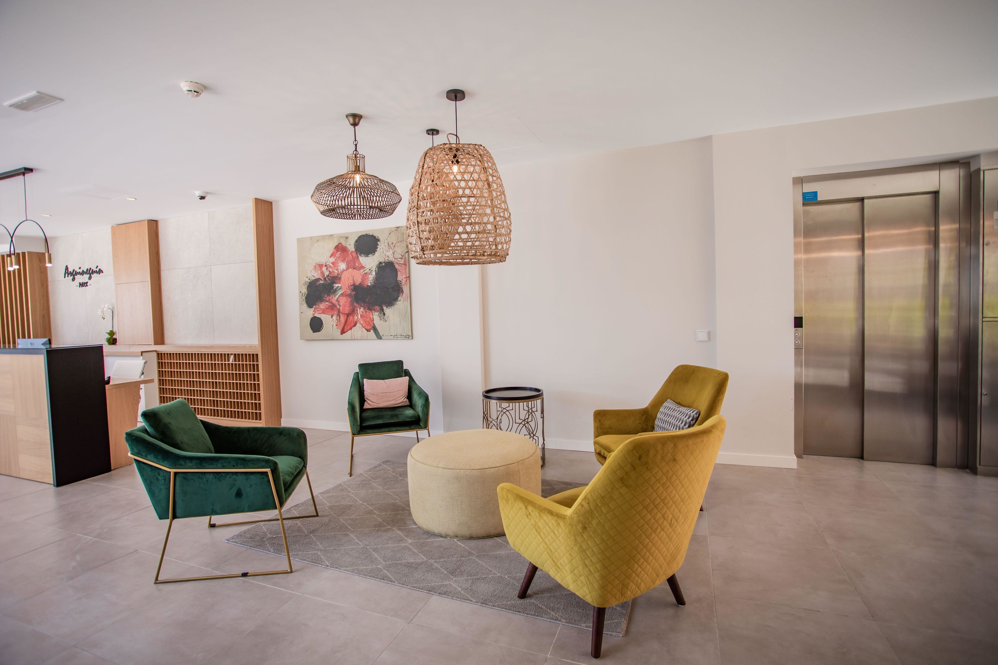 A modern living room with a green and yellow armchair, a round ottoman, and a wooden sideboard.