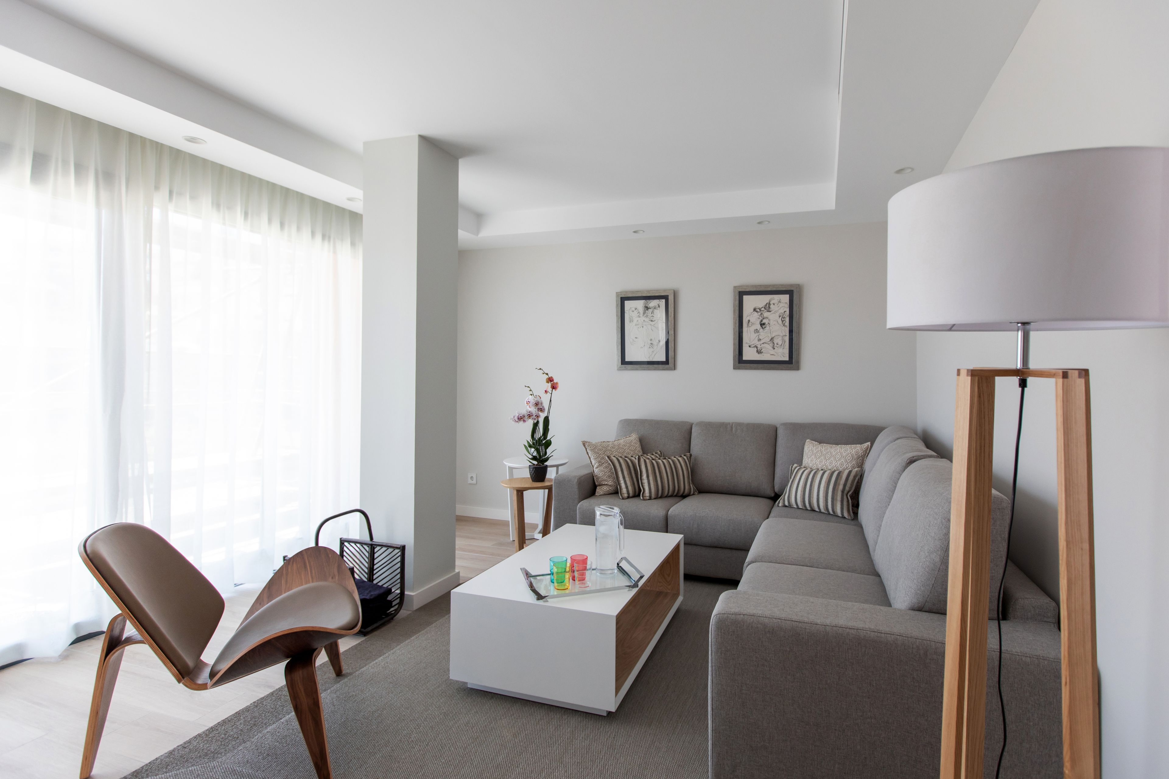 Una sala de estar moderna con un sofá, dos sillones, una mesa de centro y una lámpara.