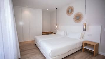 Une chambre moderne avec un grand lit, des tables de chevet en bois et deux appliques murales.