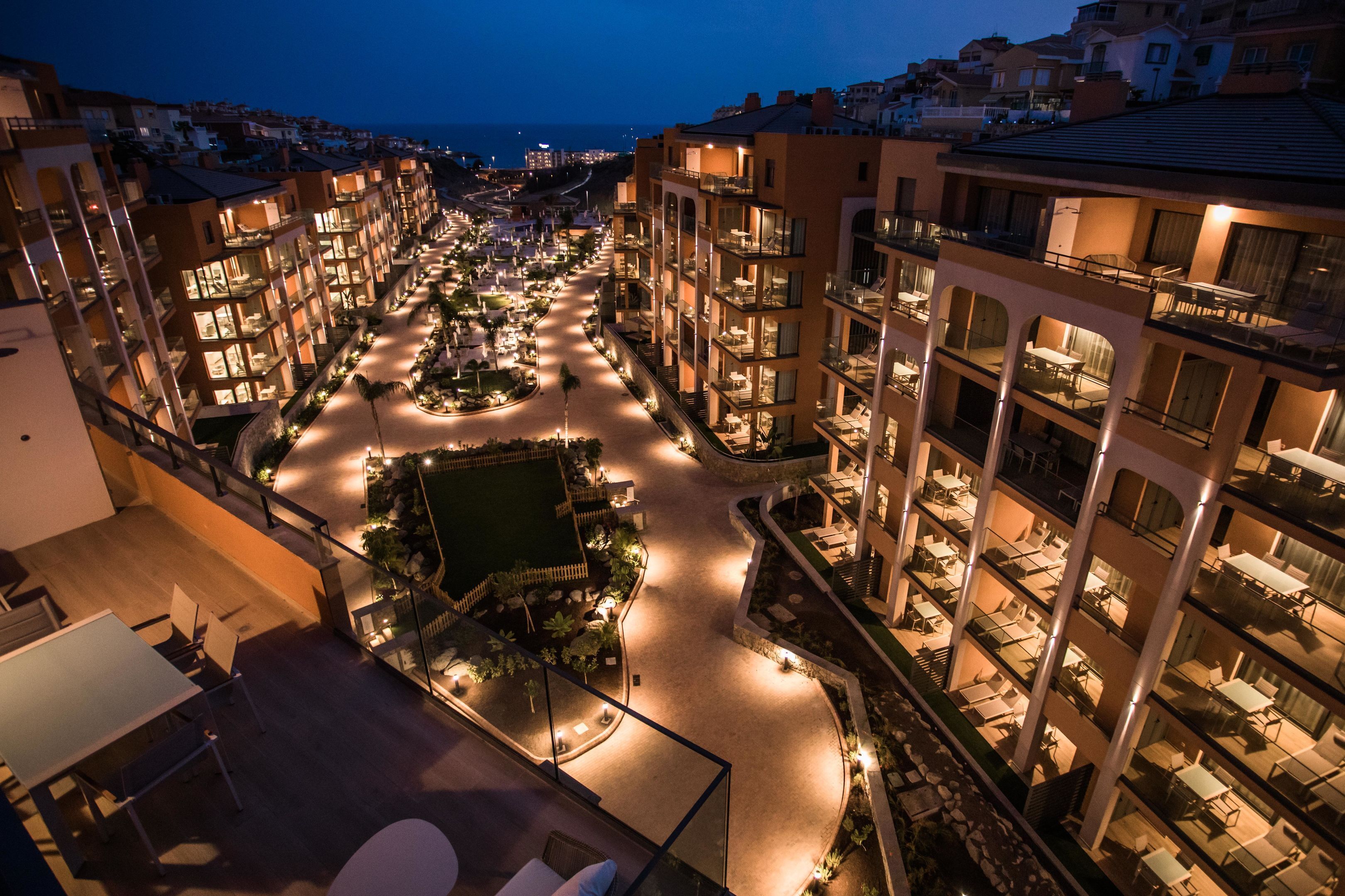 Un hotel de varios pisos con un patio central, asientos al aire libre y balcones.