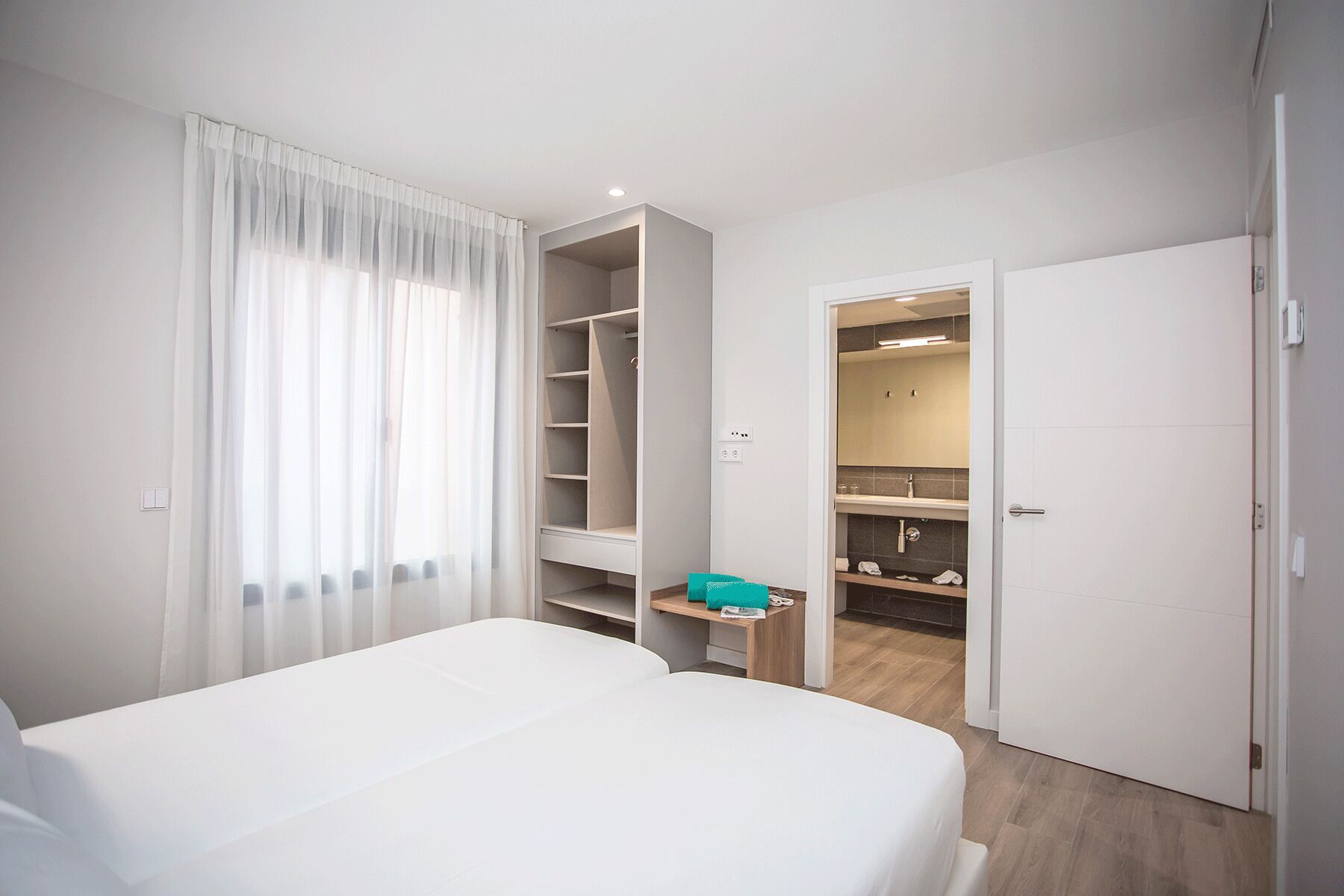 A hotel room with a bed, a walk-in closet, and a bathroom with a mirror and sink.