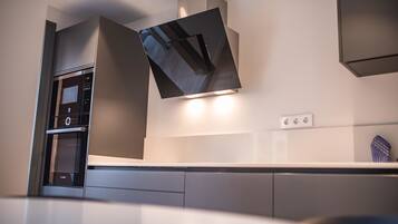 A modern kitchen with a built-in oven, a microwave, and a stainless steel range hood.