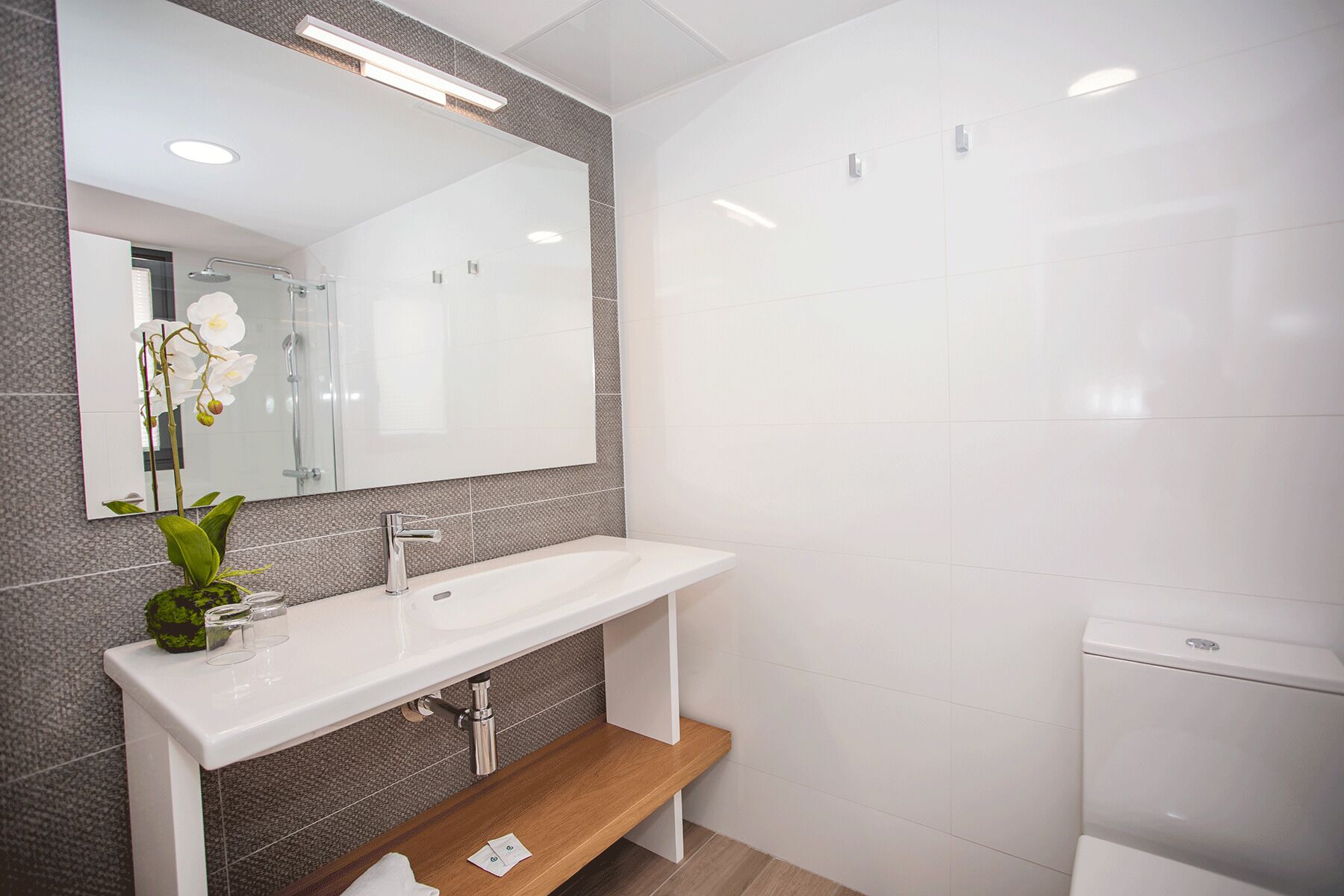 A modern bathroom with a white sink, a mirror, and a toilet.