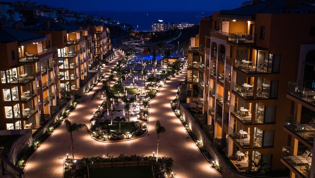 A multi-story hotel with a central courtyard, outdoor seating areas, and balconies.