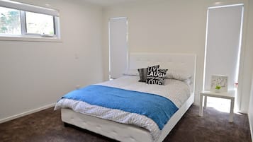 Un dormitorio con cama, mesita de noche, ventana y puerta.