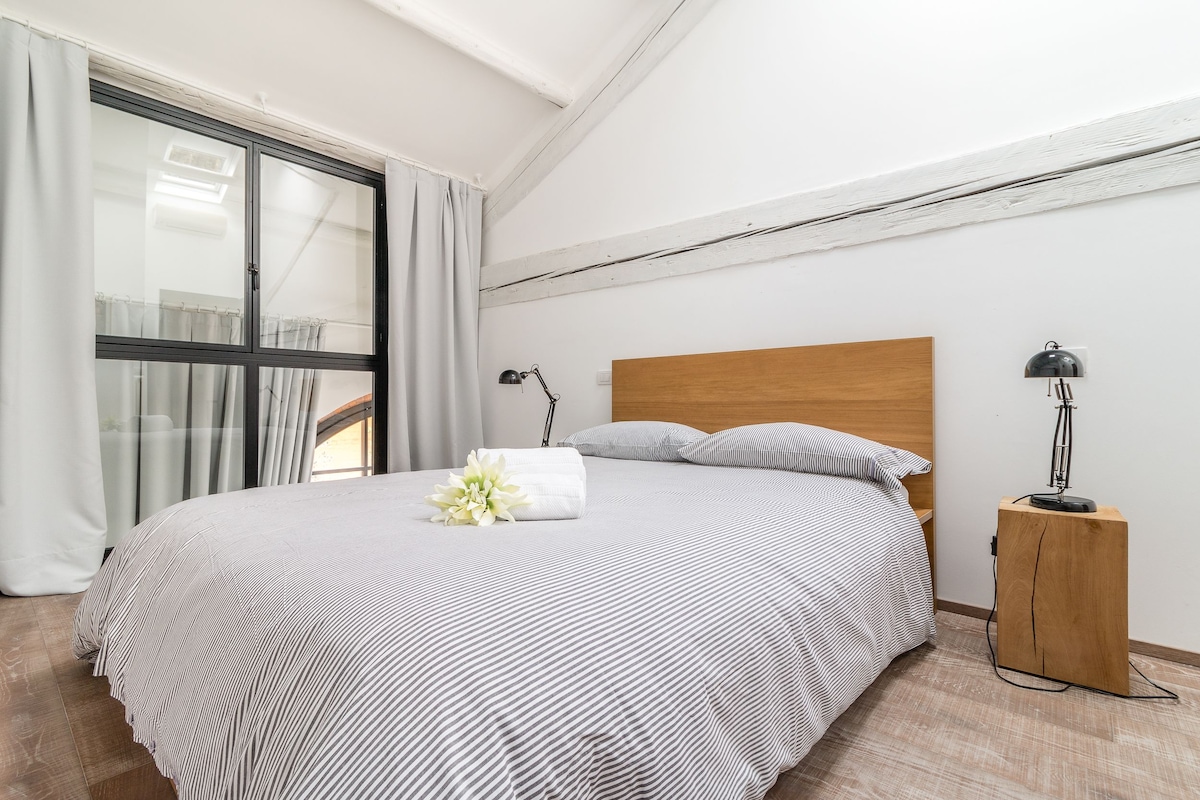 Un lit bien fait, avec une couvre-lit à rayures, une tête de lit en bois et une lampe de chevet.