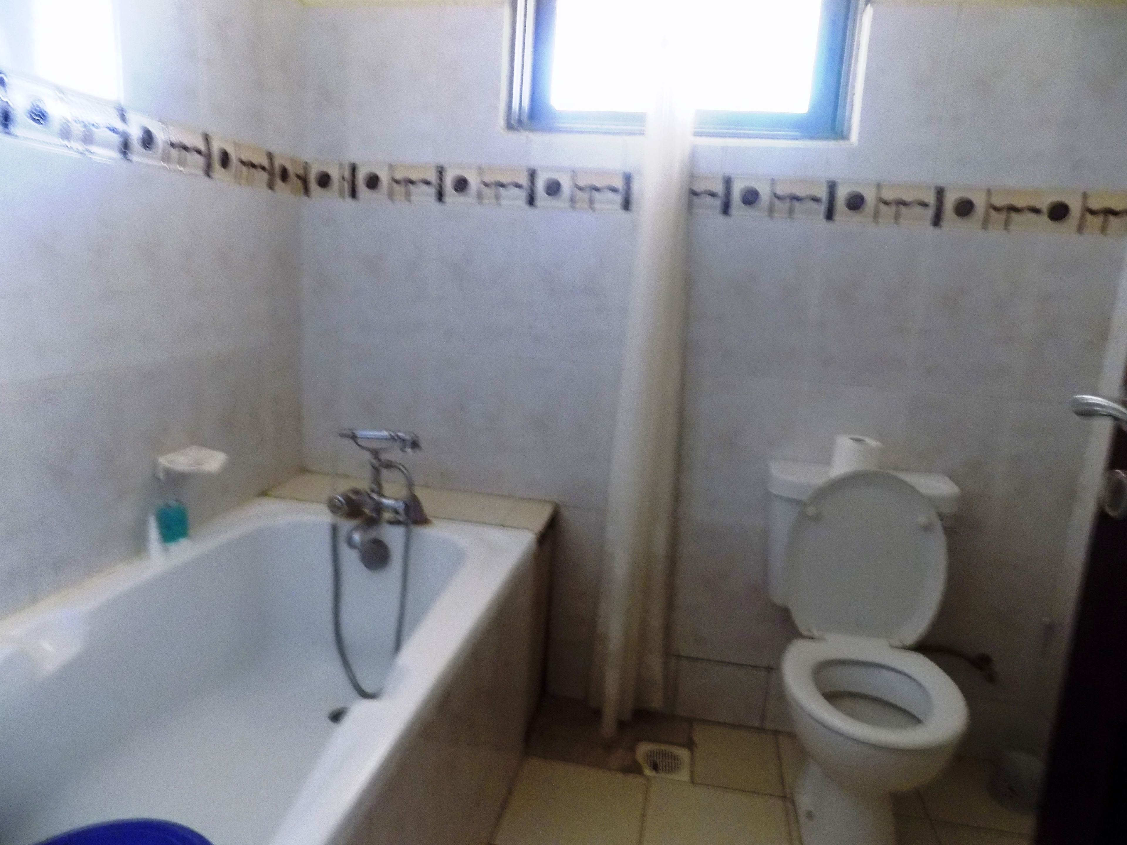 A bathroom with a bathtub, toilet, and a window.