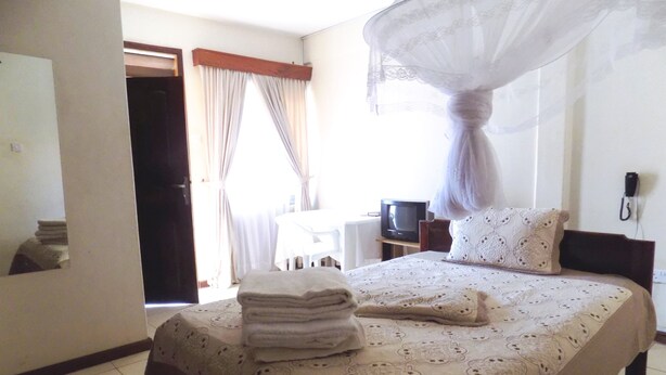 A hotel room with a bed, a TV, a bedside table, and a telephone.