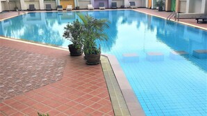A swimming pool with a tiled deck, potted plants, and lounge chairs.