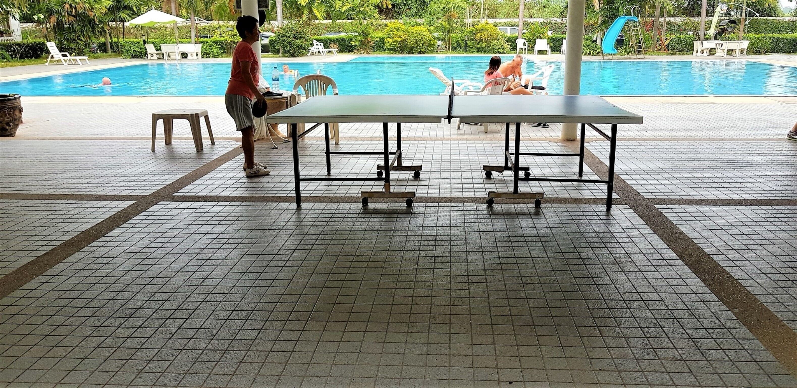 A tiled indoor pool area with lounge chairs and a table.