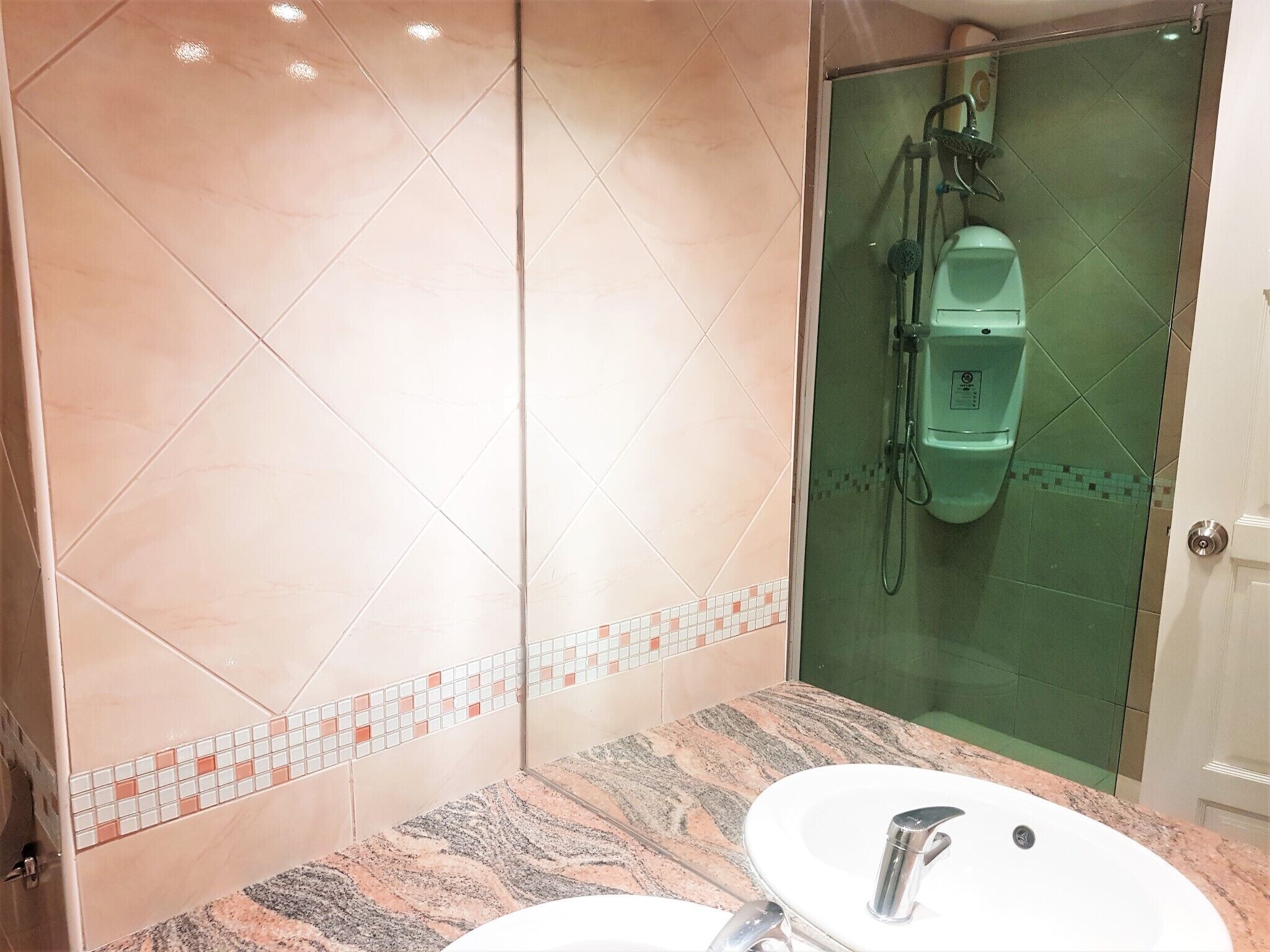 Ein Badezimmer mit Marmorwaschbecken, einer Glaskabine für die Dusche und einer gefliesten Wand.