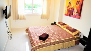 A hotel room with a bed, a TV, a window with curtains, and a painting on the wall. - Park Lane Resort Jomtien Beach (Pattaya)
