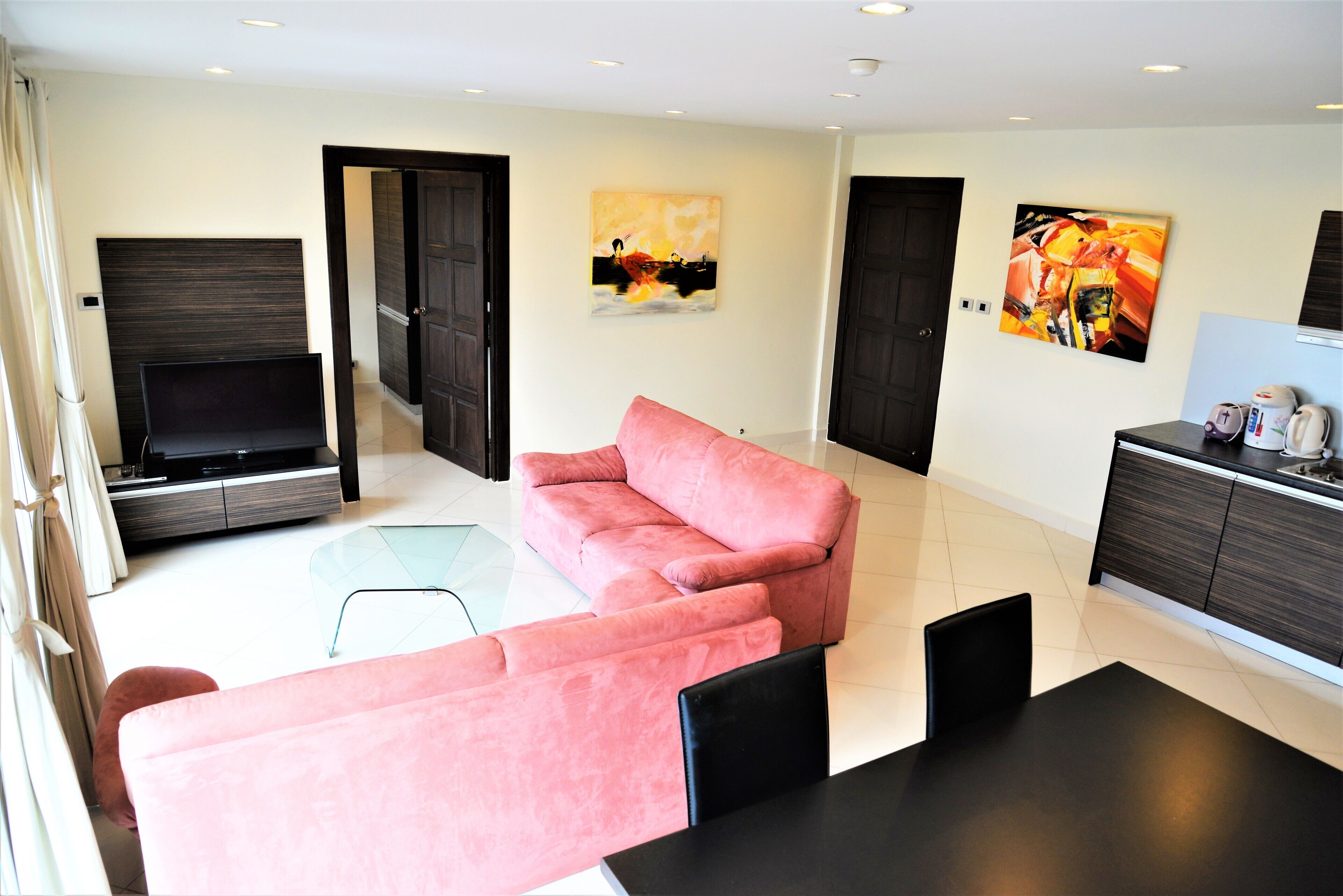 A modern living room with a pink sofa, a flat-screen TV, and artwork on the walls.