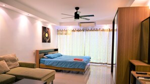 Une chambre à coucher moderne avec un lit, un canapé, un meuble pour la télévision et un ventilateur de plafond.