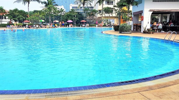 A large outdoor swimming pool with clear blue water, surrounded by lounge chairs and umbrellas. - Lovely Studio at View Talay 1 (Pattaya)