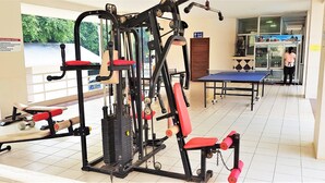 A gym with exercise equipment, a ping pong table, and a refrigerator. - Sea View Studio Jomtien (Pattaya)