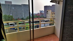 A balcony with a view of a cityscape, including high-rise buildings and a school.