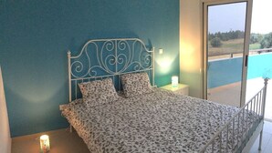 A bedroom with a bed, a nightstand, and a window with a view of a pool. - Luxury oasis with garden near beach and airport (Tersefanou)