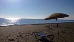 A beach with a single umbrella and a chair. - Luxury oasis with garden near beach and airport (Tersefanou)