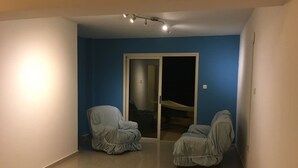 A room with two covered chairs, a sliding glass door, and a ceiling light fixture. - Luxury oasis with garden near beach and airport (Tersefanou)