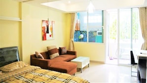 Un dormitorio moderno con cama, sofá, mesa de centro y un ventanal con vistas al exterior.