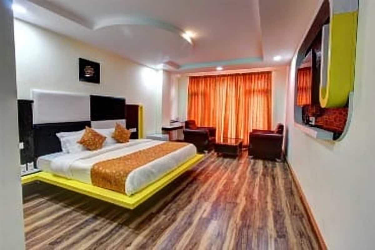 Ein Hotelzimmer mit Bett, Schreibtisch, Stuhl und einem fenster mit Vorhängen.