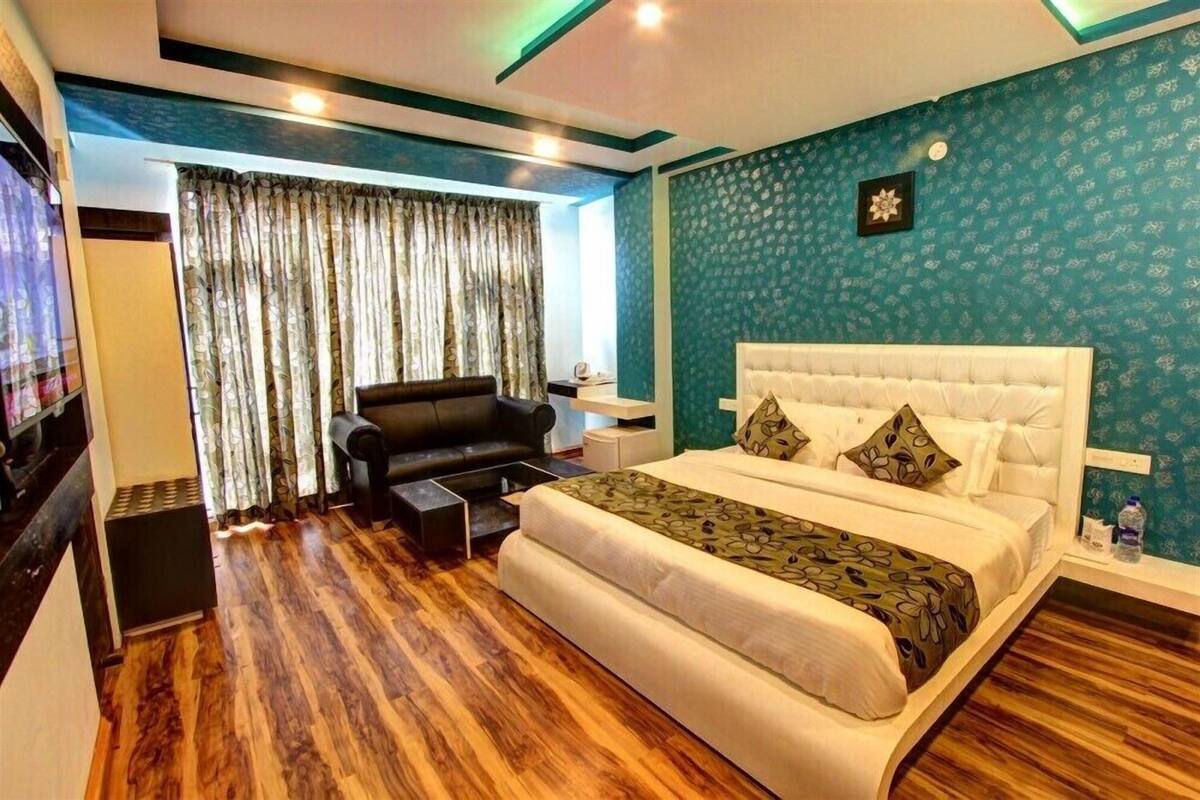 Ein Schlafzimmer mit einem großen Bett, einer schwarzen Ledersofa, einem kleinen Tisch und einem Fernseher.