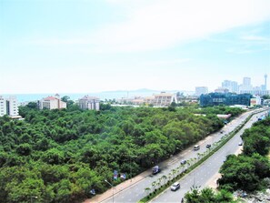 A highway with multiple lanes, surrounded by dense greenery and buildings in the background.