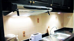 A kitchen with a black countertop, a stainless steel sink, a white toaster, and a microwave. - Sea View Condo - Jomtien Beach (Pattaya)