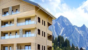 Un hotel de varios pisos con balcones y montañas al fondo.