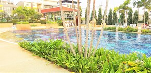 A swimming pool with lounge chairs and palm trees.
