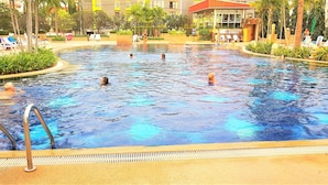 A swimming pool with multiple people swimming and lounging. - Studio Condo at Jomtien Beach (Pattaya)