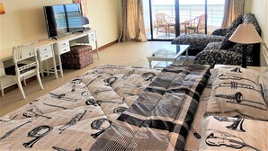 Ein Hotelzimmer mit Bett, Schreibtisch, Fernseher und einem Balkon mit Gartenmöbeln.