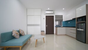 Una sala de estar moderna con un sofá, una mesa de centro y una zona de cocina con armarios y electrodomésticos.