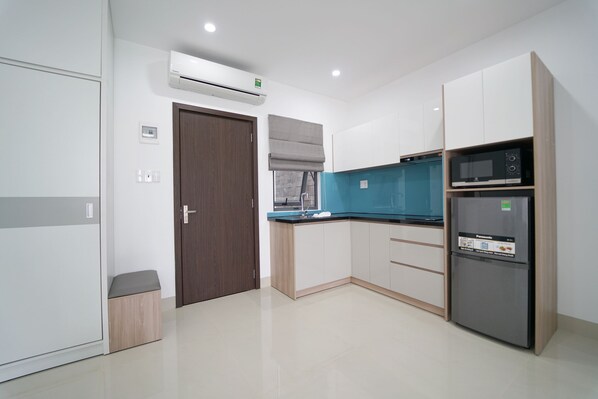 Una cocina moderna con gabinetes blancos, microondas integrado y refrigerador.