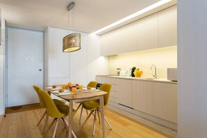 Eine moderne Küche mit weißen Schränken, einem Holztisch und gelben Stühlen.