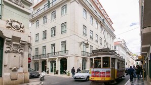 A street scene with a tram, a building with balconies, and pedestrians. - JOIVY Sunny 1-bed flat w/terrace&sea view in Baixa,3mins to Arco da Rua Augusta (Lisboa)