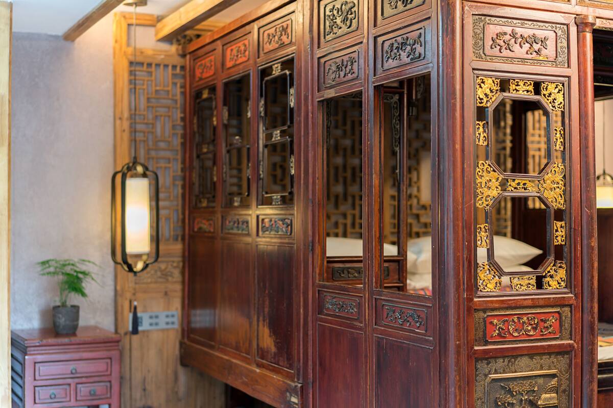 Une pièce traditionnelle en bois, ornée de sculptures complexes et dotée d’un grand miroir aux détails dorés raffinés.
