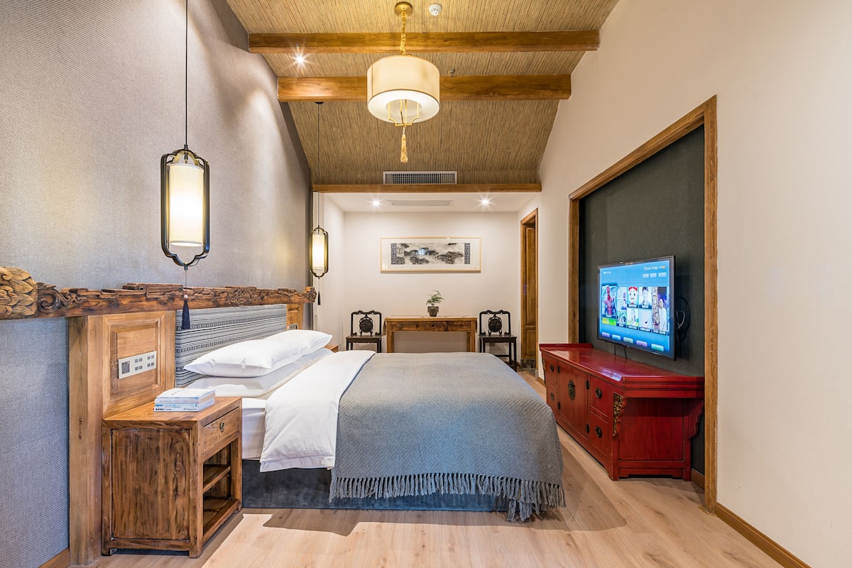 Une chambre à coucher avec un lit, une table de chevet, une télévision et des meubles en bois.
