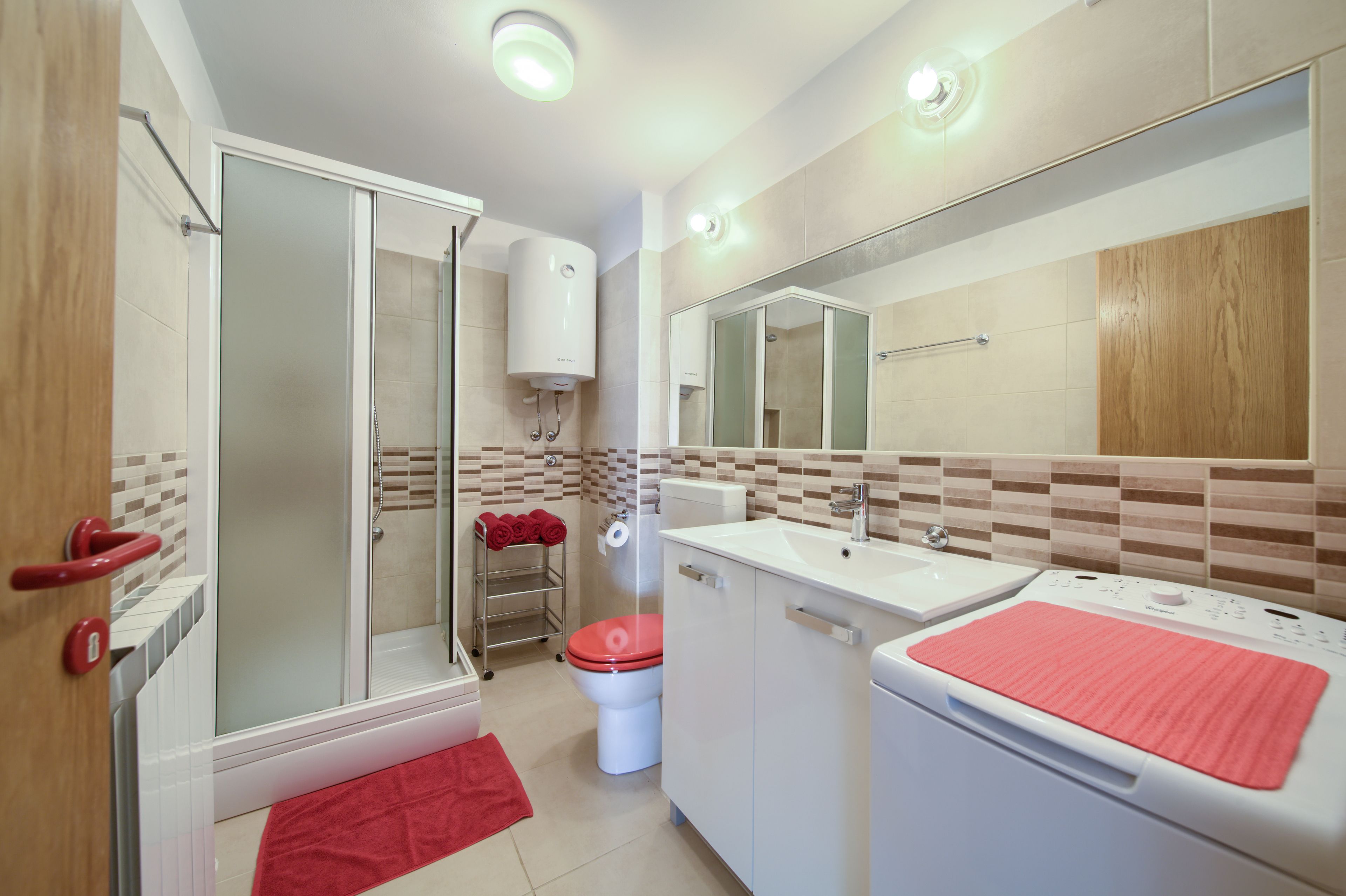 A modern bathroom with a glass shower enclosure, a white sink, a toilet, and a mirror.
