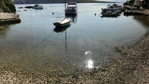 A calm harbor with boats docked, a bridge in the background, and a rocky shoreline. - Apartments Six (Kraljevica)