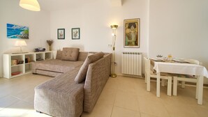 A living room with a sofa, a dining table set, and a radiator. - Apartments Six (Kraljevica)